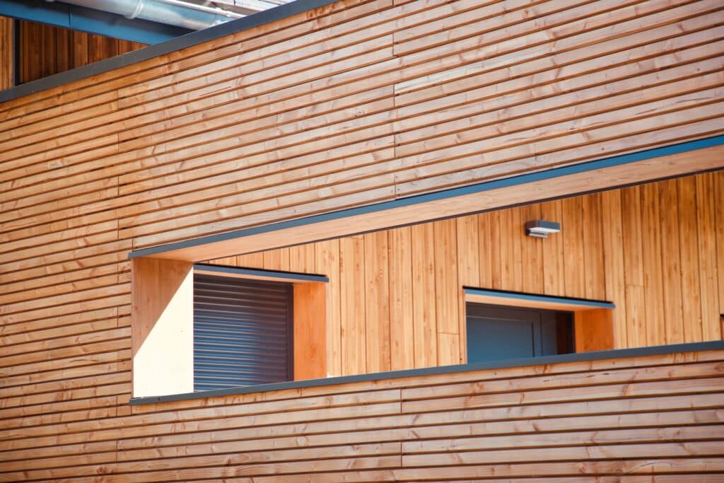 Façade Bois Moderne: Revêtement Lames, Architecture Durable Façade moderne en bois clair à lames horizontales, avec une grande ouverture révélant des fenêtres et un volet roulant. Architecture.